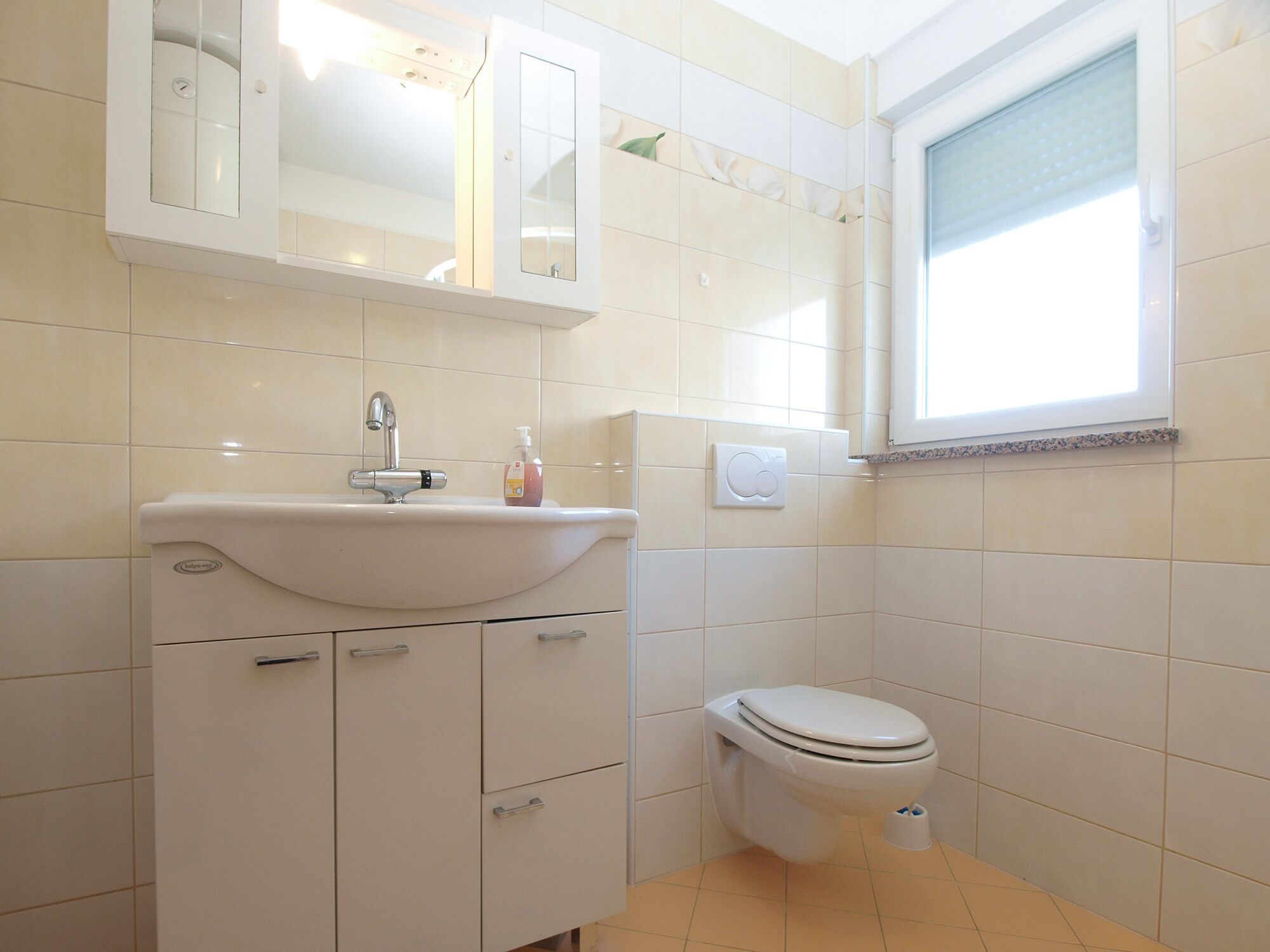 Ein Badezimmer mit Waschbecken, Spiegel und Toilette.