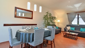 Uma sala de jantar com uma mesa posta para quatro pessoas, um sofá e uma mesa de centro.