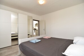 A bedroom with a bed, a wardrobe, and a mirror reflecting a bathroom. - Apartment 1938 (Vodnjan)