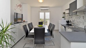 Een moderne keuken met een eethoek, met een televisie, een koffieapparaat en een potplant.