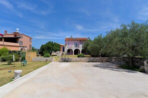 A rural road leading to a traditional building with a stone facade and arched windows.