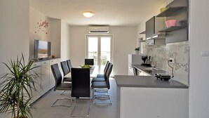 Een moderne keuken met een eethoek, met een flatscreen televisie, een eettafel met stoelen en een potplant.