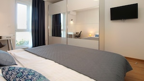 A modern hotel room with a large bed, a desk, a chair, a flat-screen TV, and a large mirror. - House 1939 (Pula)