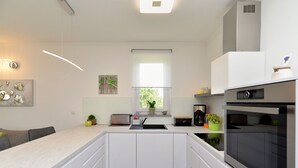 Una cocina moderna con armarios blancos, horno empotrado y ventana que proporciona luz natural.
