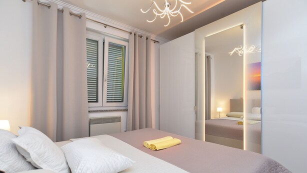 Un dormitorio moderno con cama, cortinas, un radiador y un espejo.