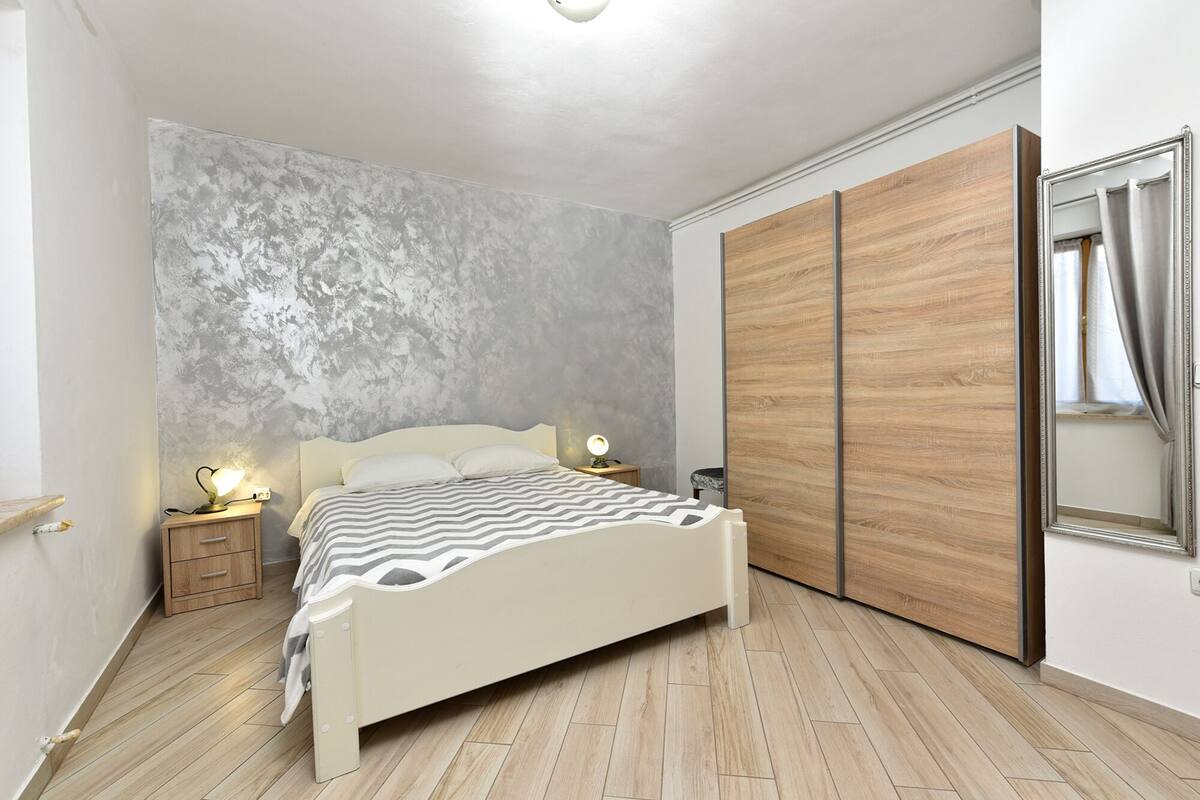A bedroom with a bed, bedside lamps, a wardrobe, and a mirror.