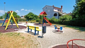 Un parque infantil con columpios, toboganes y bancos.