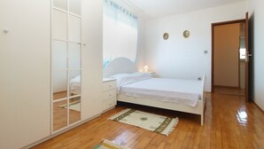Un dormitorio con cama, armario, mesita de noche y una puerta que da a otra habitación.