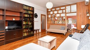 A living room with a sofa, a TV, and a bookshelf. - Apartment 1947 (Fazana)
