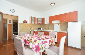 A compact kitchen with a dining table, chairs, and basic appliances. - Apartment 1947 (Fazana)
