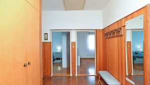 A room with wooden walls, a bench, a mirror, and a door leading to another room. - Apartment 1947 (Fazana)