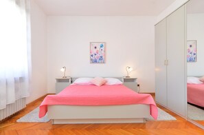 A bedroom with a bed, bedside tables, a mirror, and artwork on the wall. - Apartment 1947 (Fazana)