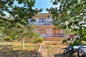 A two-story building with a balcony, a small garden area, and outdoor seating. - Apartment 1947 (Fazana)