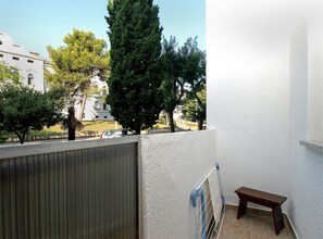 Enjoy the view from this balcony with a metal railing and a comfortable bench, overlooking the surrounding neighborhood.