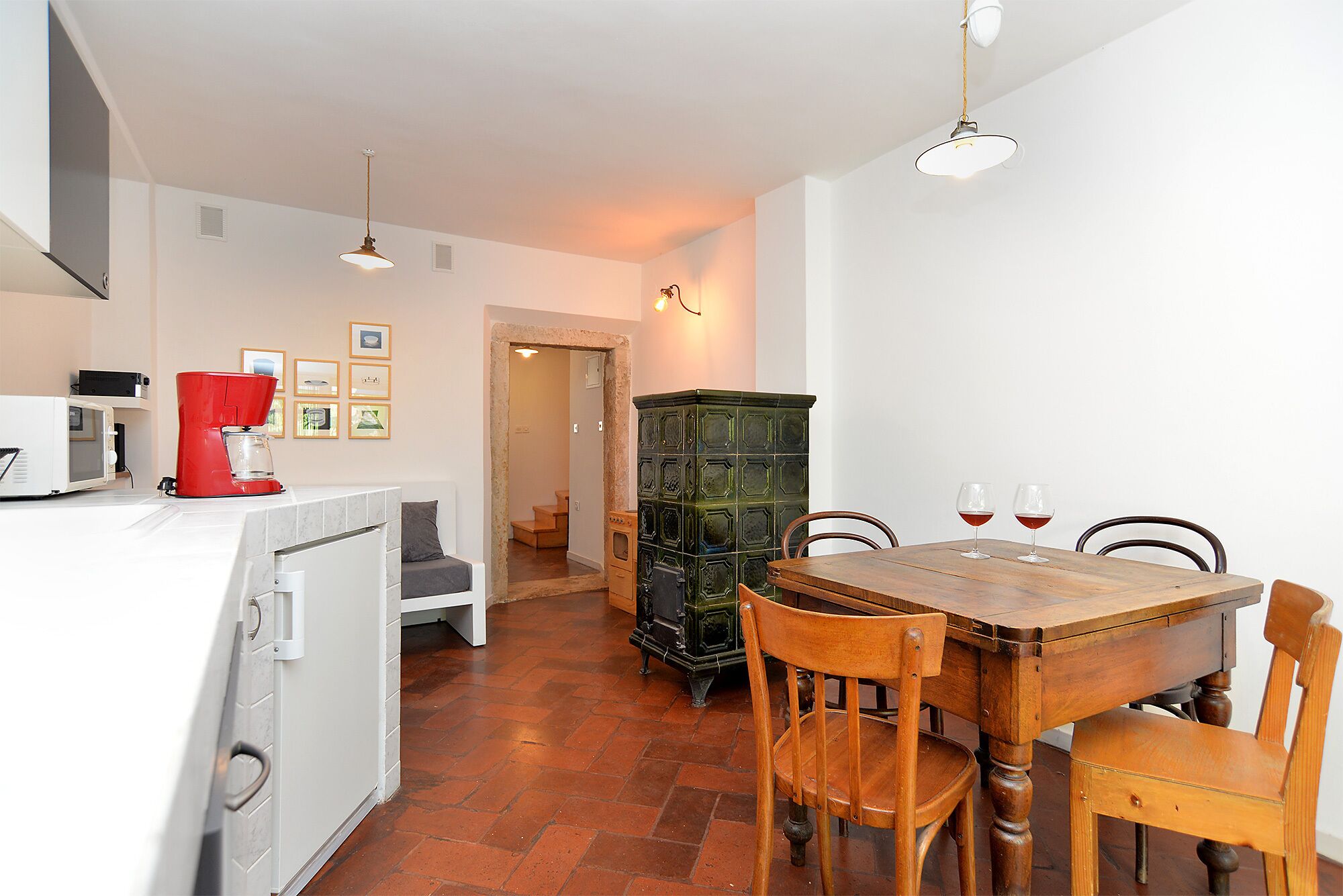 A dining area with a wooden table and chairs, a coffee machine, and a cabinet.