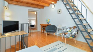 Een moderne woonkamer met een houten trap, een flatscreen televisie, een wereldbol en een fauteuil met bloemenprint.