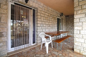 A stone-walled patio with a table and chairs. - Apartment 1954 (Fazana)