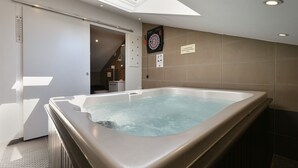 Une salle de bain moderne avec une grande baignoire, un puits de lumière et un jeu de fléchettes accroché au mur.