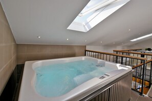 A modern bathroom with a freestanding bathtub, a skylight, and a staircase with wooden railings.