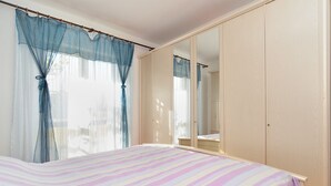 Un dormitorio con cama, armario y espejo.