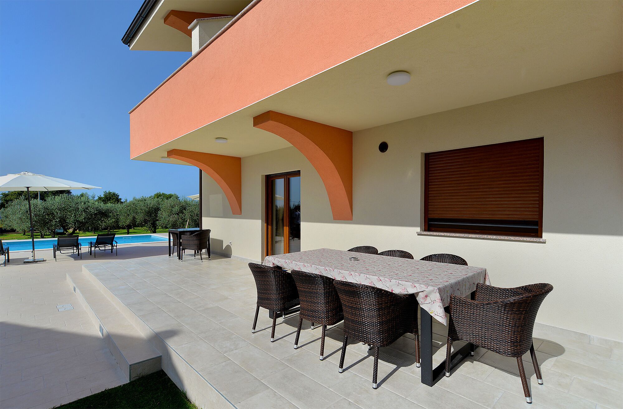 Un patio al aire libre con mesa y sillas, una piscina y cielo despejado.