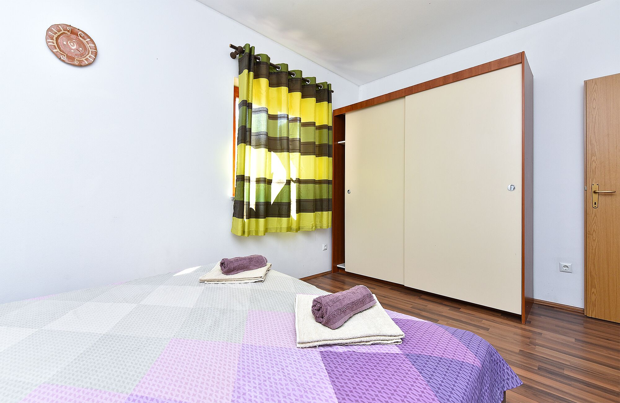 A bedroom with a bed, a wardrobe, and a curtain.