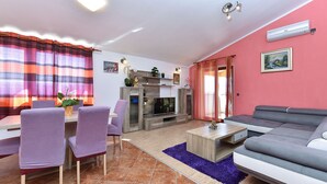 A living room with a sofa, chairs, a TV, and a dining area with a table and chairs. - House 1962 (Vodnjan)