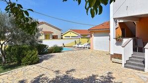 A residential area with a stone-paved courtyard, a swimming pool, and houses with red-tiled roofs. - House 1962 (Vodnjan)