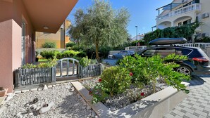 A residential area with a paved driveway, a gated entrance, and a car parked in the driveway. - Apartment 1964 (Medulin)