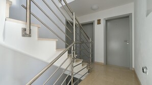 A modern interior with a staircase, a door, and a wall-mounted security device. - Apartment 1964 (Medulin)