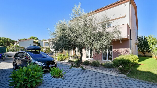 A residential building with a paved driveway and a parked car. - Apartment 1964 (Medulin)