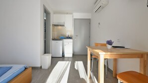 A compact kitchen with a dishwasher, a small refrigerator, and a wooden dining table with chairs. - Apartment 1964 (Medulin)