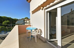 A balcony with a table and chairs, a sliding glass door, and a view of the surrounding area. - Apartment 1964 (Medulin)