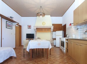 Une cuisine de taille réduite avec un coin repas, un téléviseur et une horloge au mur.