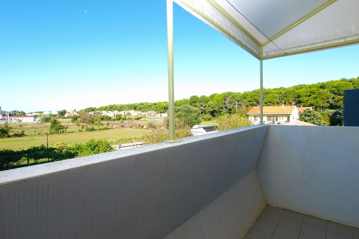 A balcony with a view of a green landscape and buildings in the distance.