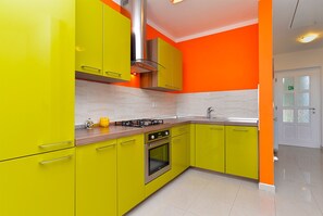 A kitchen with bright yellow cabinets, a stainless steel range hood, and a modern stove. - Apartment 1966 (Umag)