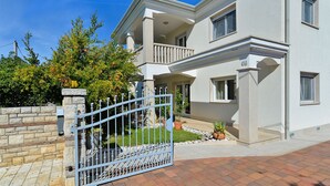 A two-story house with a gated entrance, a balcony, and a well-maintained garden. - Apartment 1966 (Umag)