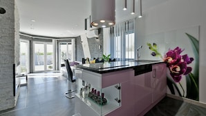 A modern bathroom with a glass shower enclosure, a large mirror, and a pink vanity.
