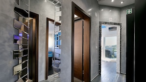 A modern hallway with a mirrored wall, a wooden door, and a view of the outside.
