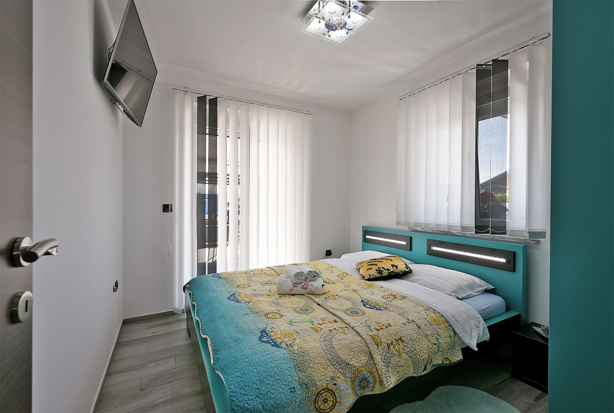 A bedroom with a bed, a nightstand, a mirror, and a ceiling light fixture.