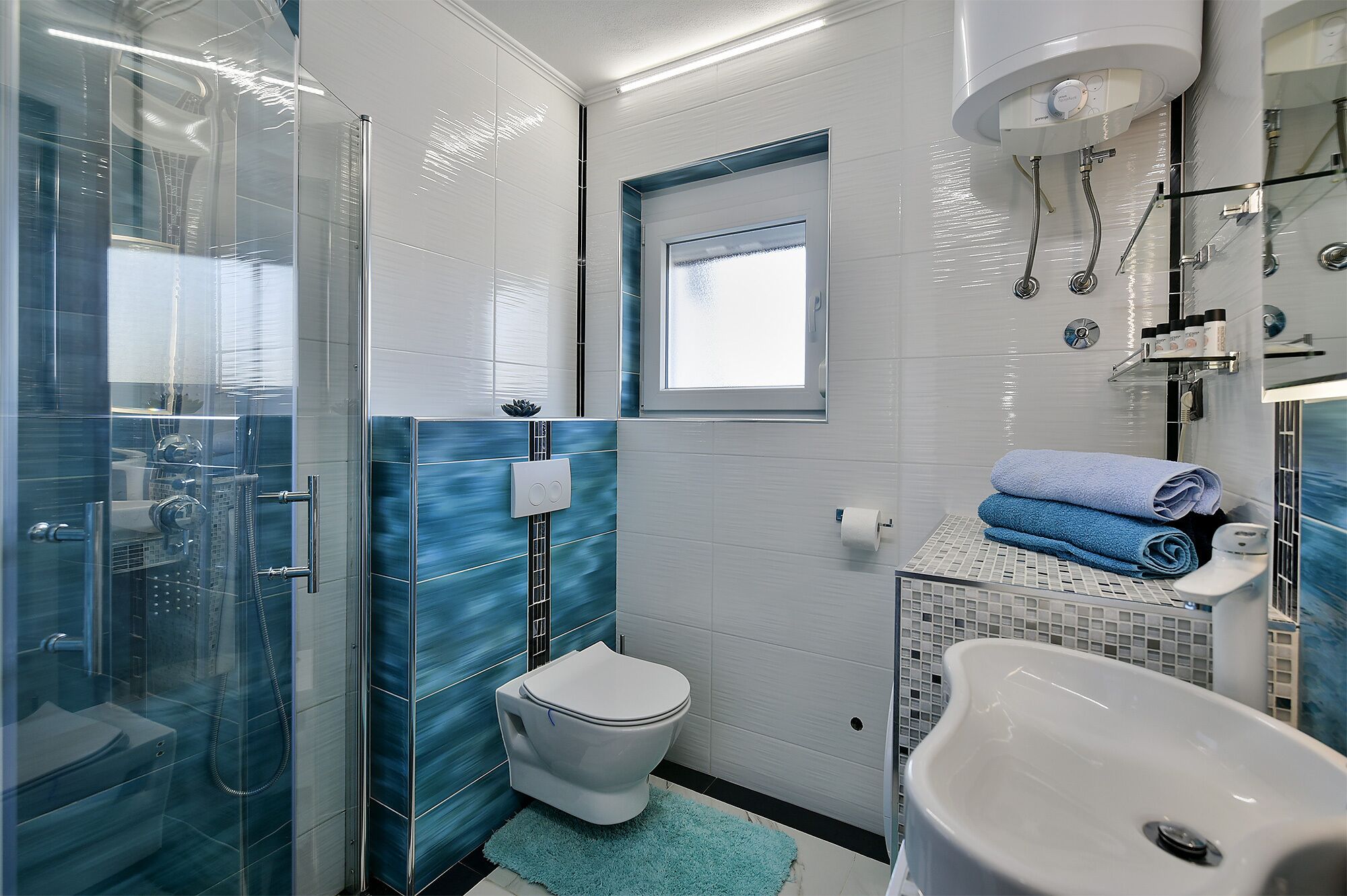 A modern bathroom with a glass-enclosed shower, a toilet, and a sink.