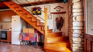 A kitchen with a wooden staircase, stone wall, and a clock. - House 1974 (Barban)