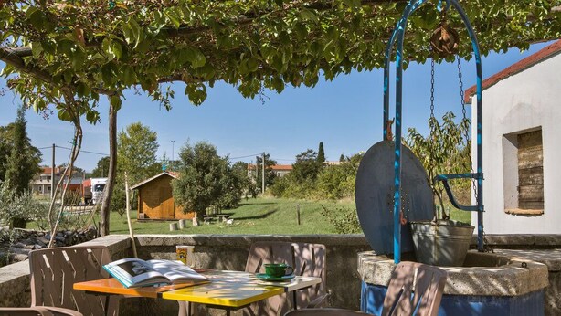 An outdoor seating area with a table, chairs, and a swing. - House 1974 (Barban)