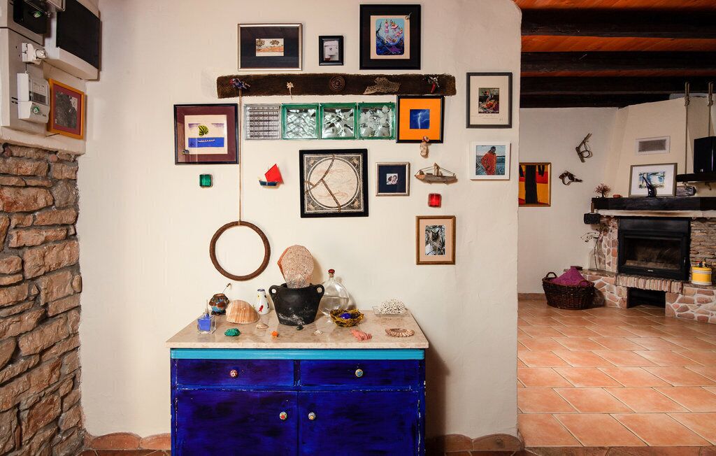 Una habitación con chimenea de piedra, un aparador azul y varias fotografías enmarcadas en la pared.