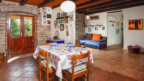 A rustic dining area with a stone wall, wooden beams, and a table set for two with bowls and plates. - House 1974 (Barban)