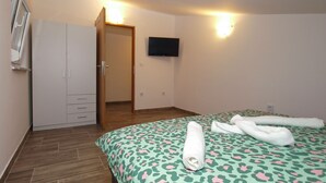 Hotellihuone, jossa on sänky, vaatekaappi, televisio ja ovi.