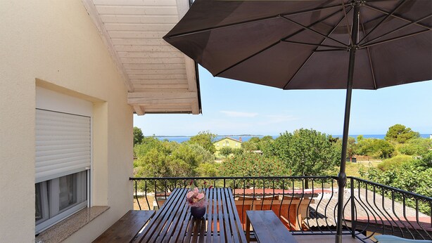 A wooden balcony with a bench, a table, and a large umbrella. - Apartment 1976 (Vodnjan)