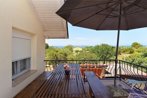 Een houten balkon met een bank, een tafel en een grote parasol.