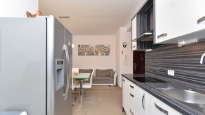 A modern kitchen with a refrigerator, stove, and dining area. - Apartment 1977 (Medulin)
