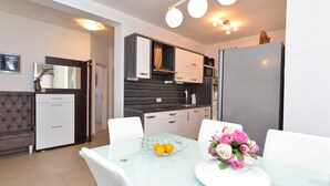 A modern kitchen with a glass dining table, white chairs, and a bouquet of flowers. - Apartment 1977 (Medulin)